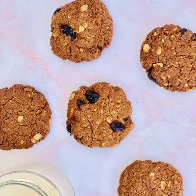 Bolachas de aveia com passas e copo de leite sobre superfície clara