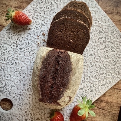 Pão escuro fatiado com morangos sobre base rendada branca