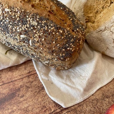 Dois pães rústicos sobre pano branco sobre mesa de madeira com fruta vermelha ao lado