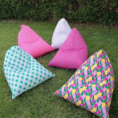 Cinco pufs triangulares coloridos con diferentes patrones sobre césped verde