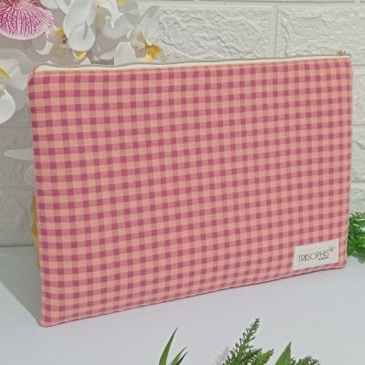 Estojo tecido xadrez tons rosa e vermelho com etiqueta TRISOPHIS e flores no fundo