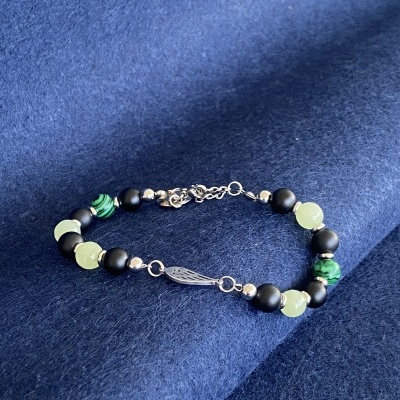 Pulseira com contas pretas, verdes e metálicas em fundo azul