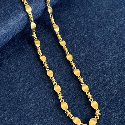 Colar dourado com elos planos sobre tecido azul escuro