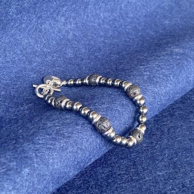 Pulseira com contas prateadas e negras sobre tecido azul escuro