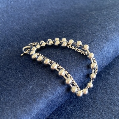 Pulseira prateada sobre tecido azul escuro