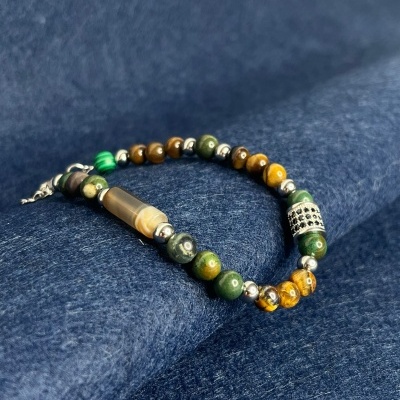 Pulseira com contas verdes e castanhas sobre tecido azul