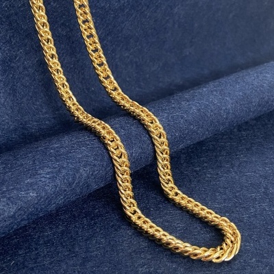 Colar dourado de elo entrelaçado sobre superfície azul