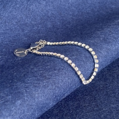 Pulseira em metal prateado com pedras brilhantes sobre tecido azul