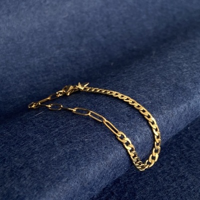 Pulseira dourada com duas correntes sobre tecido azul