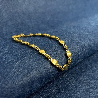 Pulseira dourada com discos numa superfície azul