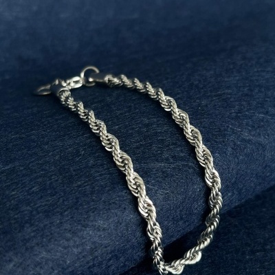 Pulseira torcido prateada sobre tecido azul escuro