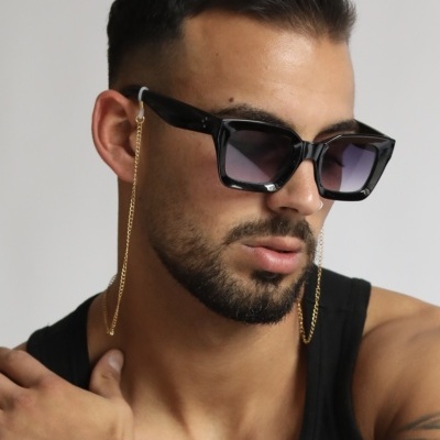 Homem com óculos de sol pretos quadrados com corrente dourada e tatuagem no braço