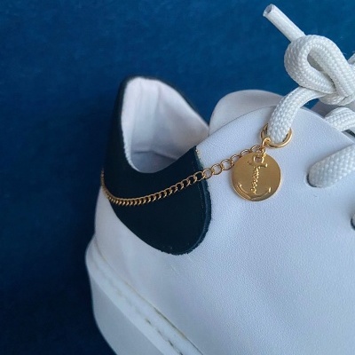 Tênis branco com detalhe preto e corrente dourada com medalha Dior