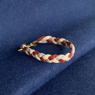 Pulseira trançada de tecido com fecho metálico sobre tecido azul escuro