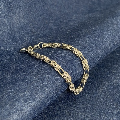 Pulseira de prata com elos intrincados sobre tecido azul escuro