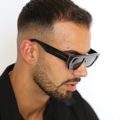 Homem a usar óculos de sol Tommy Hilfiger com armação preta e lentes cinzentas