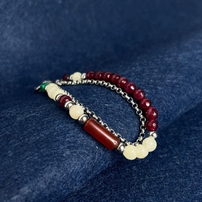 Pulseira com contas coloridas e corrente metálica sobre tecido azul