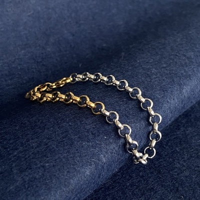 Pulseira dourada e prateada sobre tecido azul