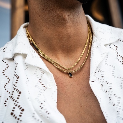 Colar triplo dourado com pendente retangular preto em pescoço de homem com camisa branca