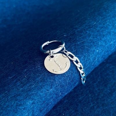 Anel de prata com pendentes disco com a palavra LOVE e âncora sobre tecido azul