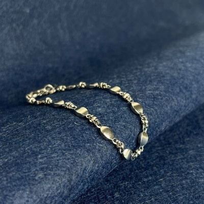 Pulseira prateada sobre tecido azul escuro texturizado