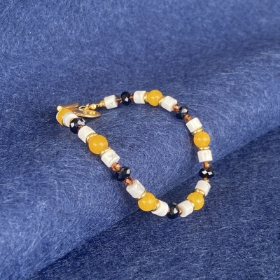 Pulseira de contas amarelas, pretas e brancas sobre tecido azul