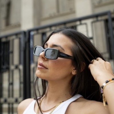Mulher de cabelo castanho com óculos de sol quadrados pretos e camiseta branca