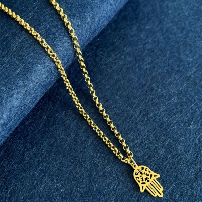 Colar dourado com pendente em forma de mão de Fátima sobre tecido azul escuro.