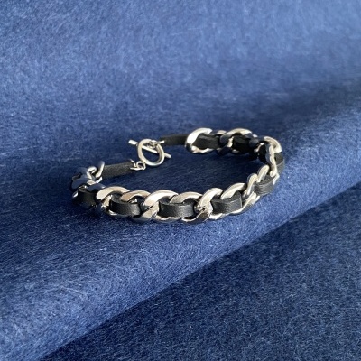 Pulseira prateada com tiras pretas sobre tecido azul