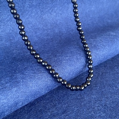 Colar de contas negras brilhantes sobre tecido azul