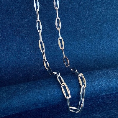 Colar metálico prata com elos geométricos sobre fundo azul