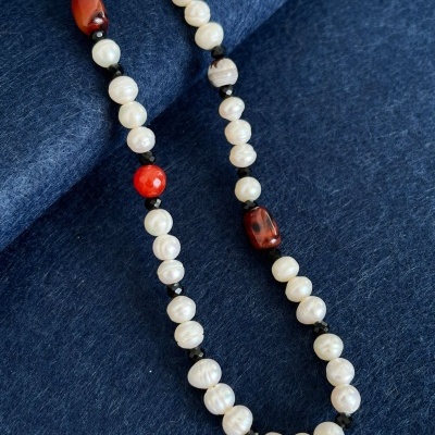 Colar de pérolas e contas coloridas sobre tecido azul escuro