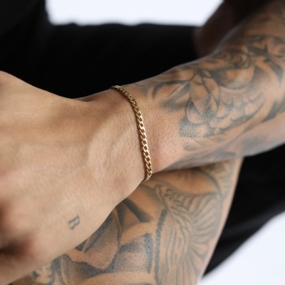 pulseira dourada de corrente no pulso com tatuagens