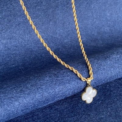 Colar dourado com pendente de flor em madrepérola sobre tecido azul-escuro