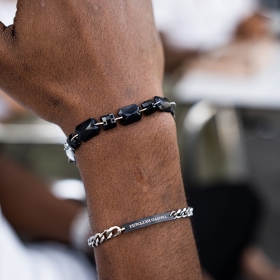 Pulso masculino com pulseiras preta de pedras e prateada com gravação TENDÊNCIA PERFEITA