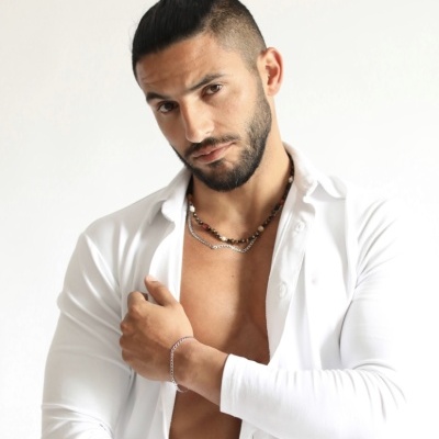 Homem com camisa branca aberta e acessórios prateados