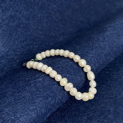 Pulseira de pérolas brancas sobre tecido azul escuro
