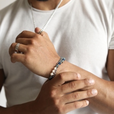 Homem com pulseira de contas coloridas, corrente prateada e anel prateado