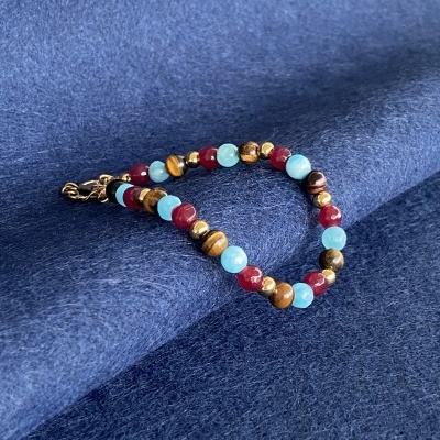 Pulseira colorida com fecho dourado sobre tecido azul escuro