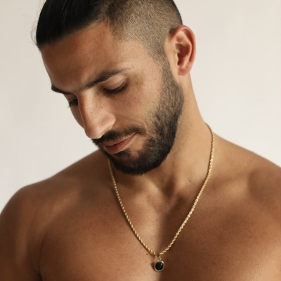 Colar masculino dourado com pendente quadrado preto em modelo masculino sem camisa