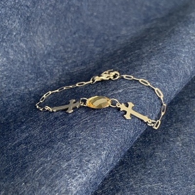 Pulseira metálica com cruzes e peça central dourada sobre tecido azul