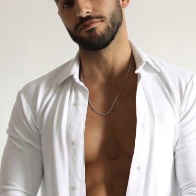 Homem com camisa branca aberta mostrando tronco e acessórios