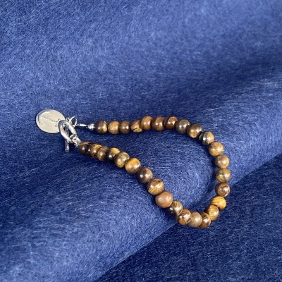 Pulseira de contas castanhas com fecho prateado sobre tecido azul