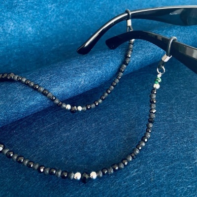 Corrente para óculos preta com contas facetadas sobre fundo azul