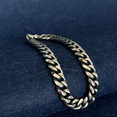 Colar de corrente prateada com elos grossos sobre fundo azul escuro