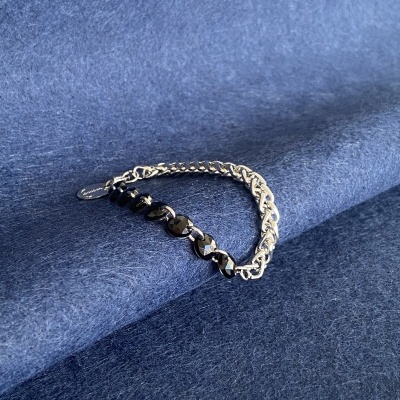 Pulseira com elos metálicos e contas pretas sobre tecido azul aveludado