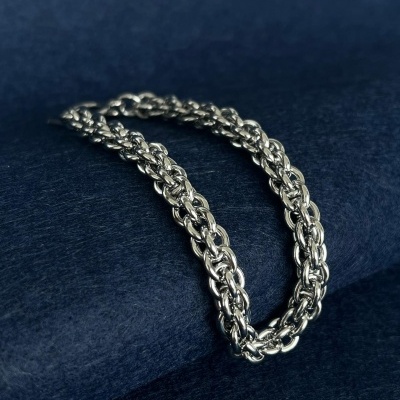 colar ou pulseira metálica prateada com elos grossos sobre tecido azul