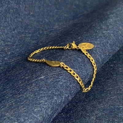 Pulseira dourada com elos finos sobre tecido azul escuro