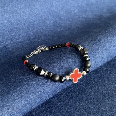 Pulseira com contas pretas e pendente vermelho em tecido azul