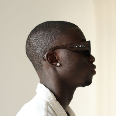 Pessoa de perfil com óculos de sol pretos com a palavra TROPO